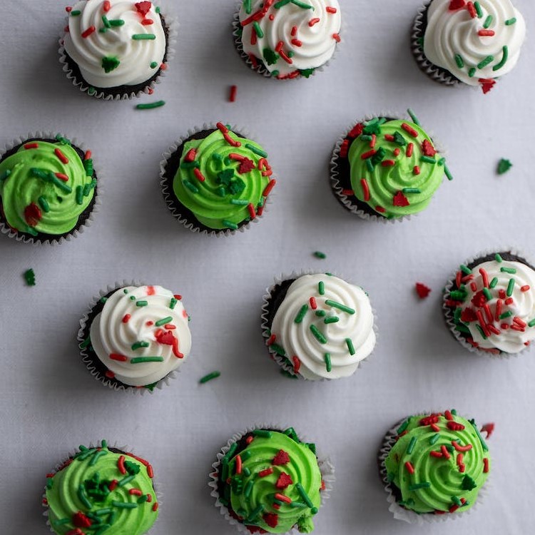 Bolinhos cupcake com cobertura e granulado, vistos de cima.